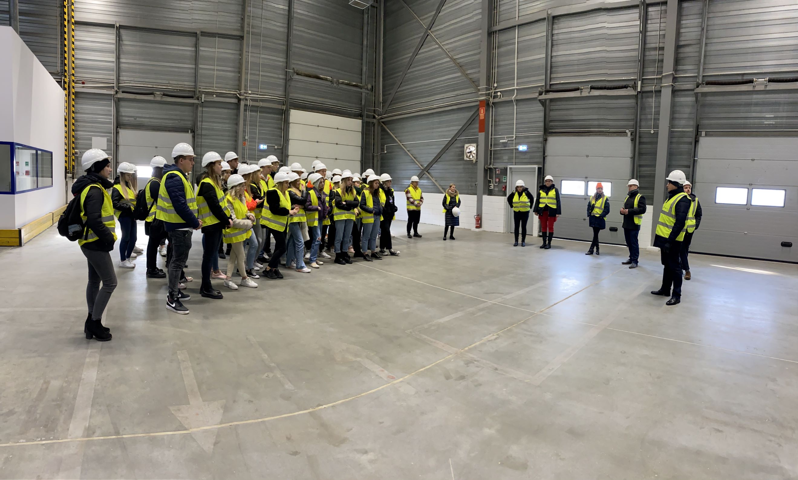 group of students in reflecitve vests inside the warehouse