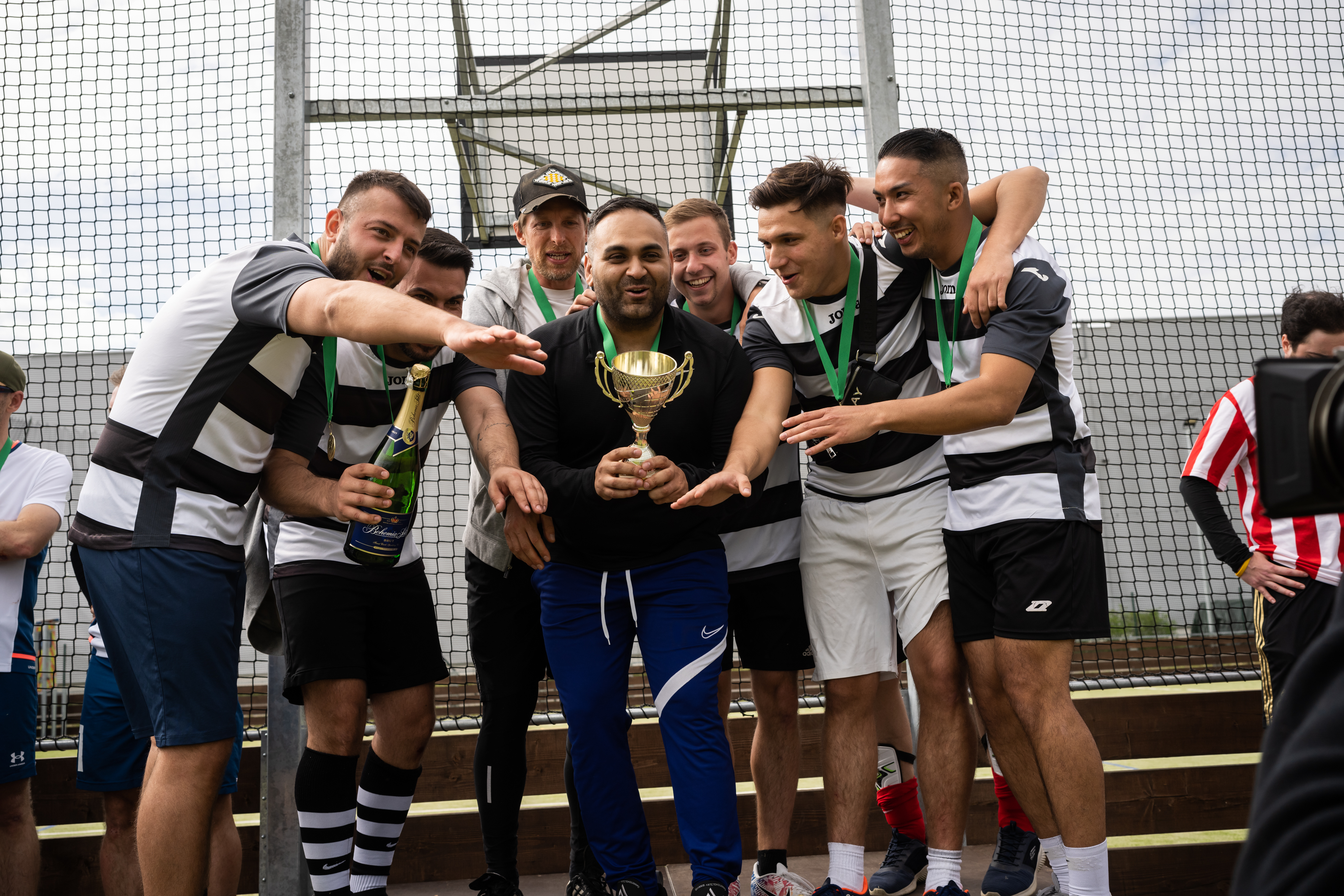 6 football players in black and white shirts on podium