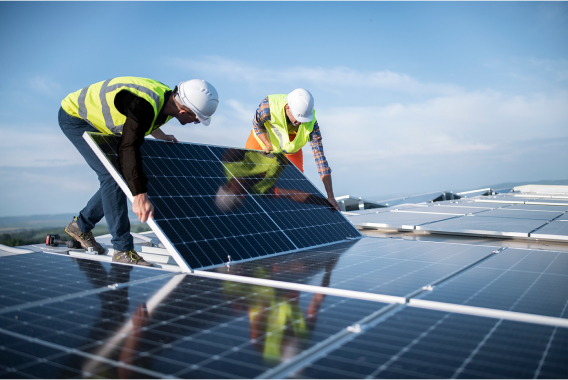 sol-energy-commercial-industrial-solutions-worker-hardhat-holding-solar-panel-rooftop