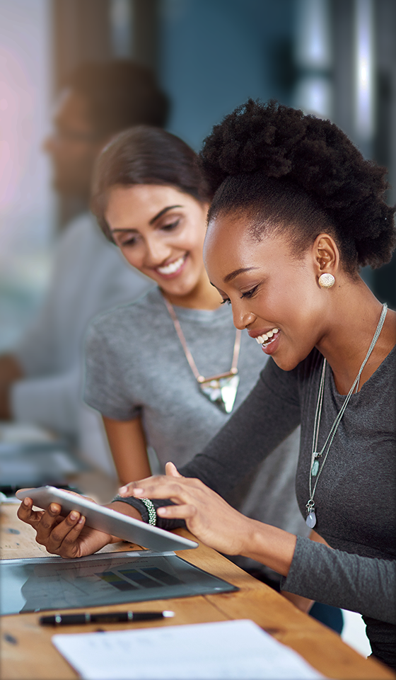 Two women smiling and looking at a tablet